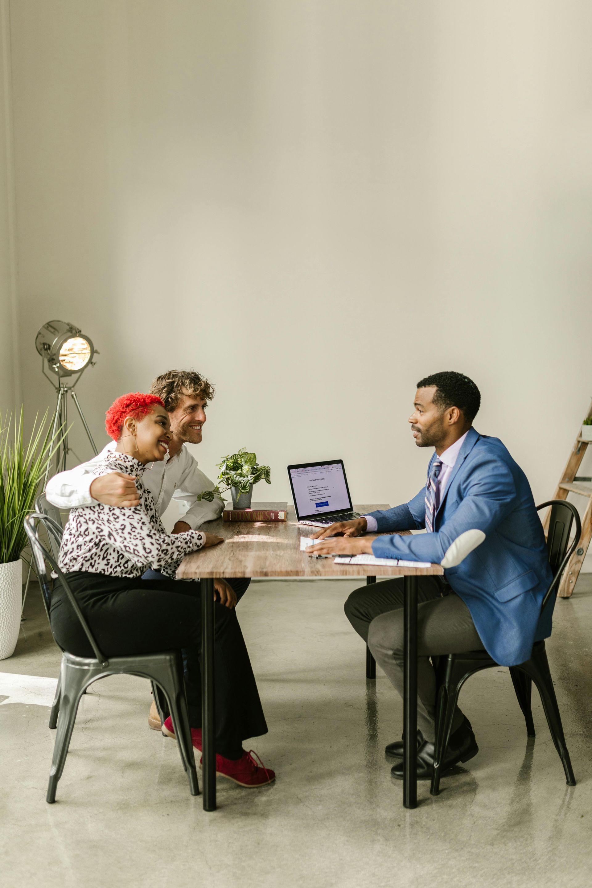 A man is sitting at a table talking to a couple.