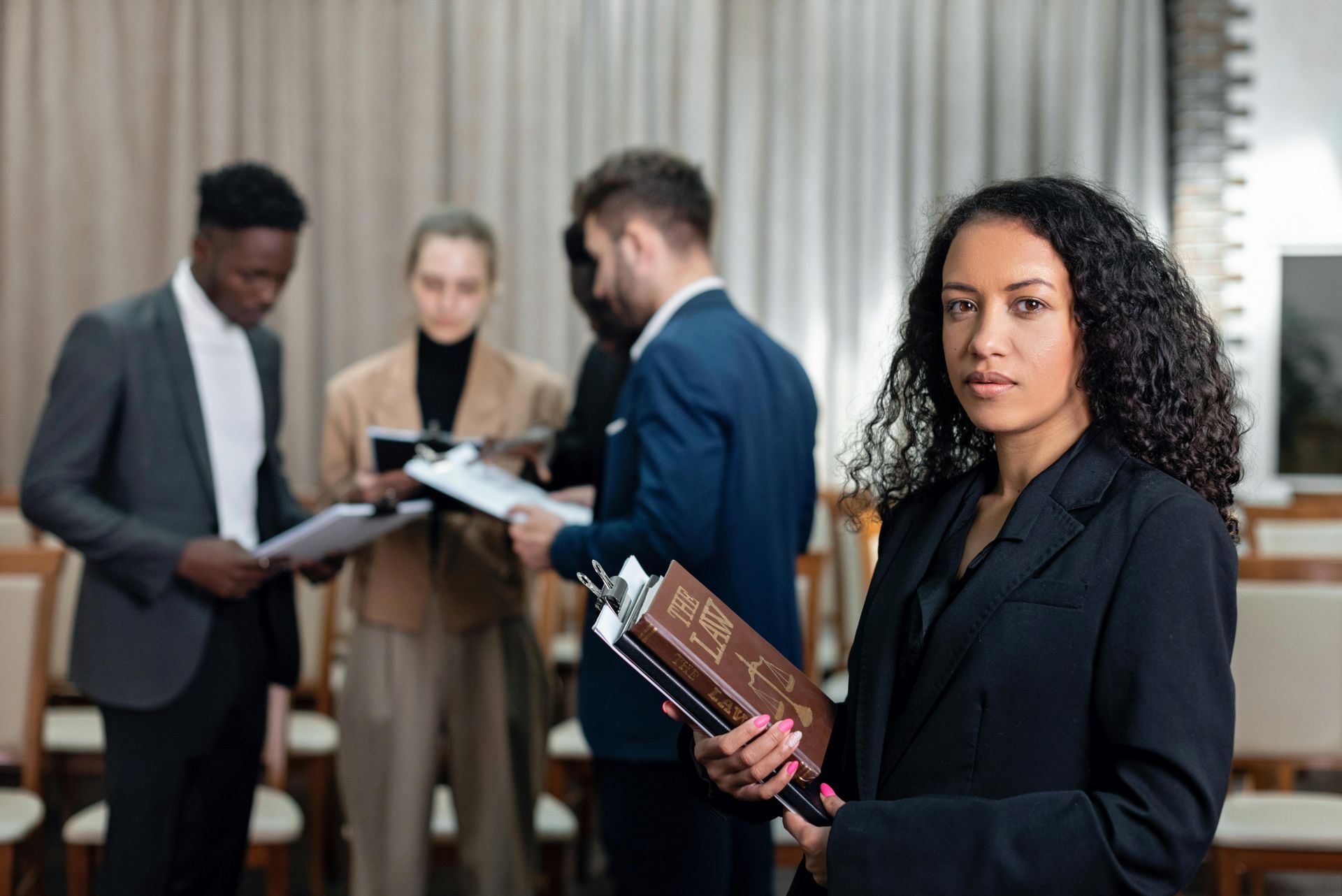 A woman is holding a book in front of a group of people.