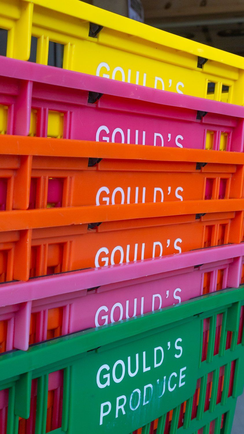 A stack of colorful plastic crates that say gould 's produce