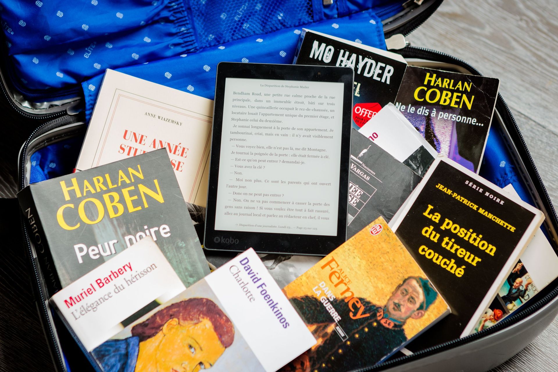 Pila di libri cartacei e eBook Kindle all'interno di una valigia
