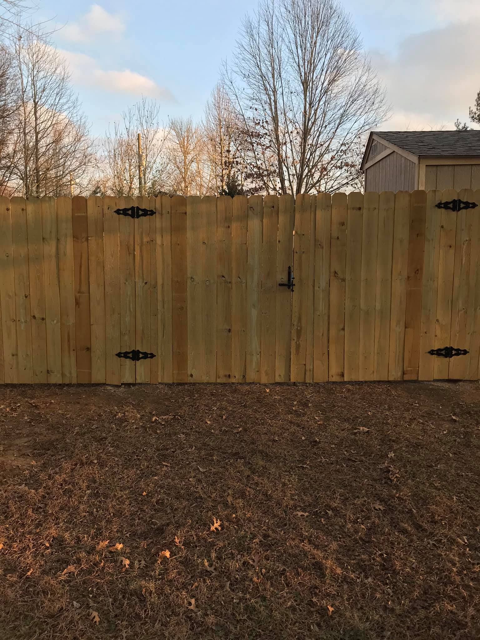A wooden fence is sitting on top of a pile of gravel in a yard.