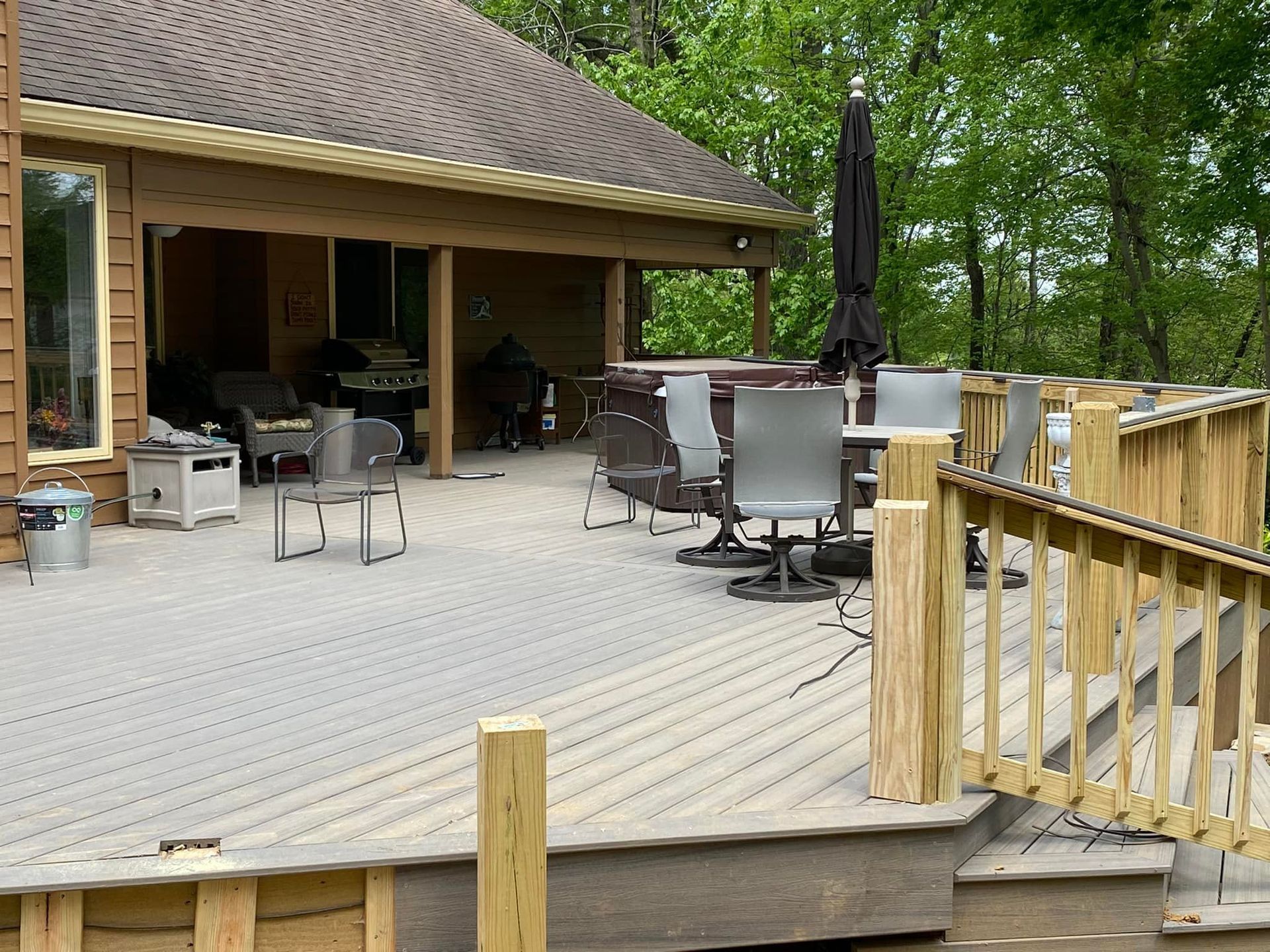 Outdoor patio with composite decking and stone steps leading to a house. Brown, gray, and white tones.