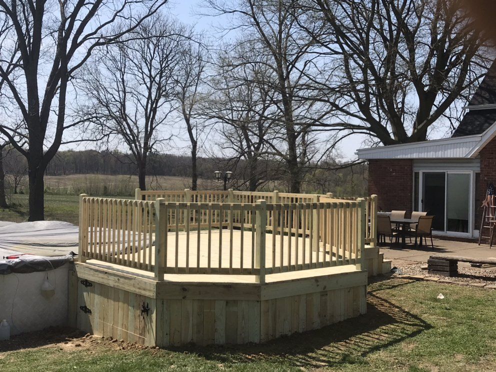 A wooden deck with a hot tub in the backyard of a house.