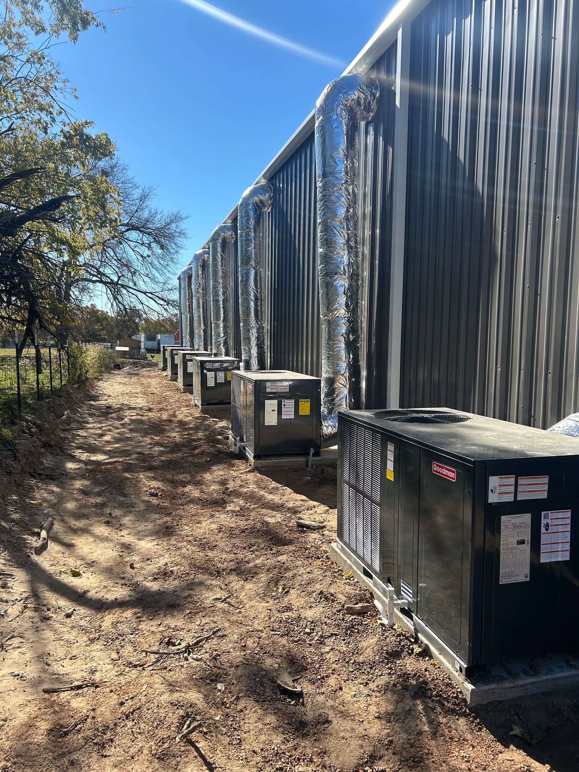 Black industrial building with metallic ductwork and air conditioning units along the side.