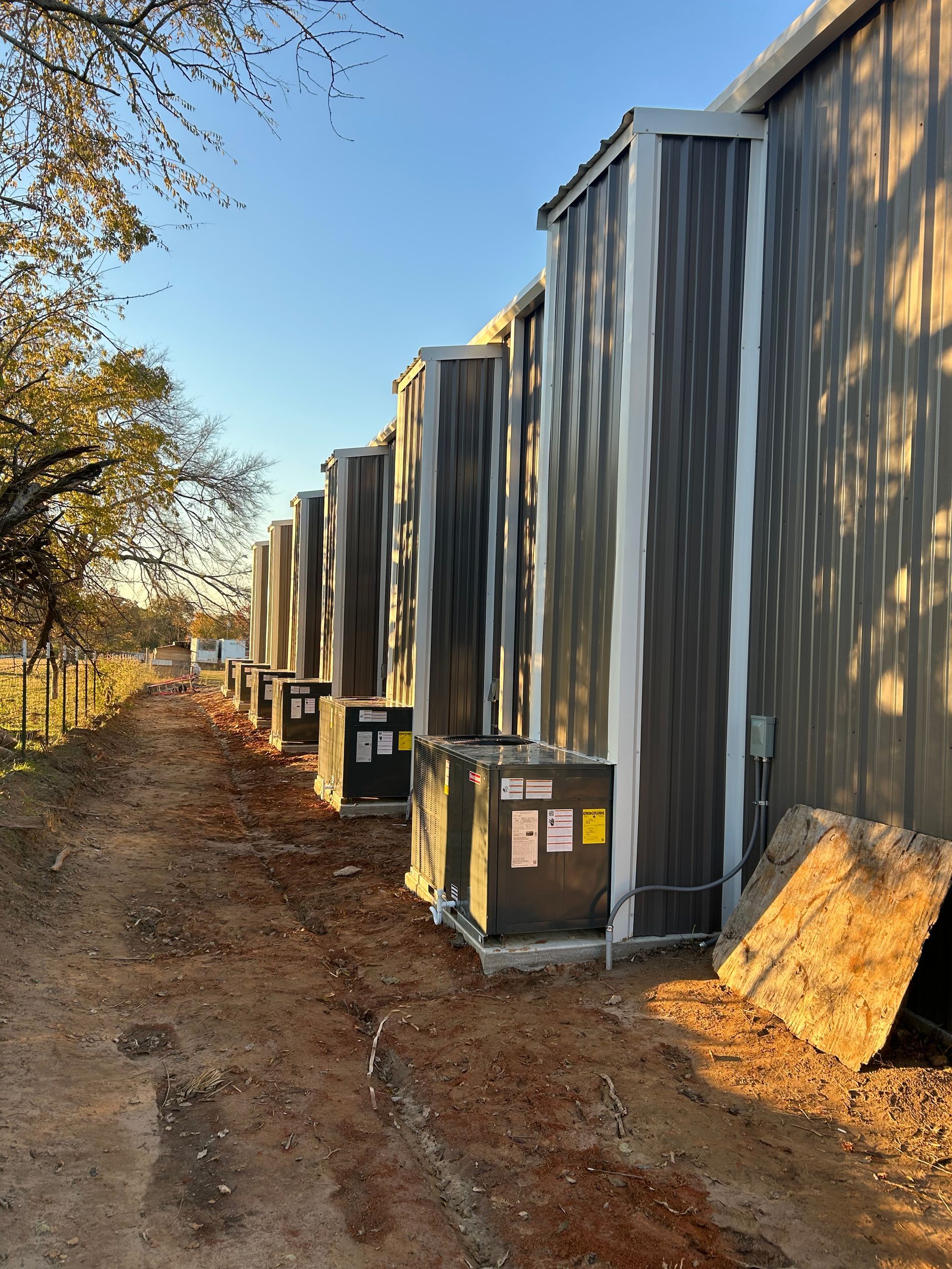 Row of gray air conditioning units along a building's exterior.