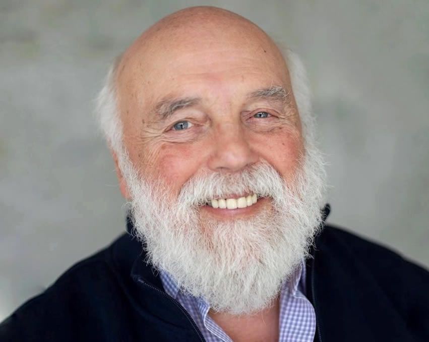 Smiling bearded man in a dark jacket against a gray background