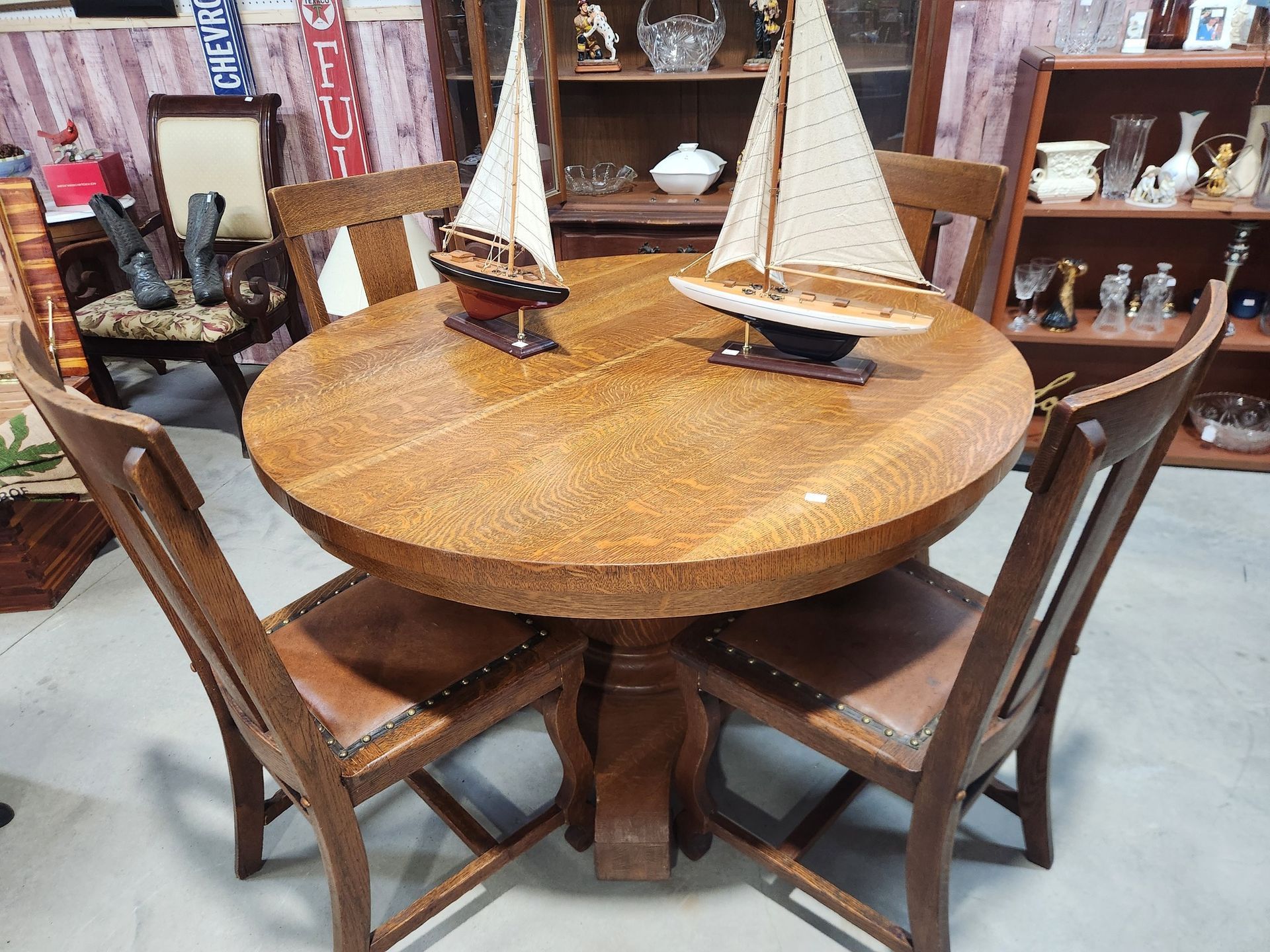 Round wooden dining table with four chairs, sailboat decor.