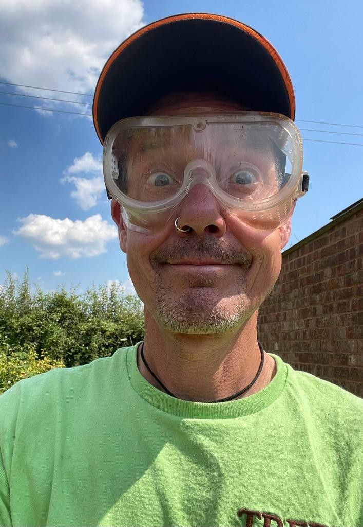 A man wearing a green shirt and goggles is making a funny face.