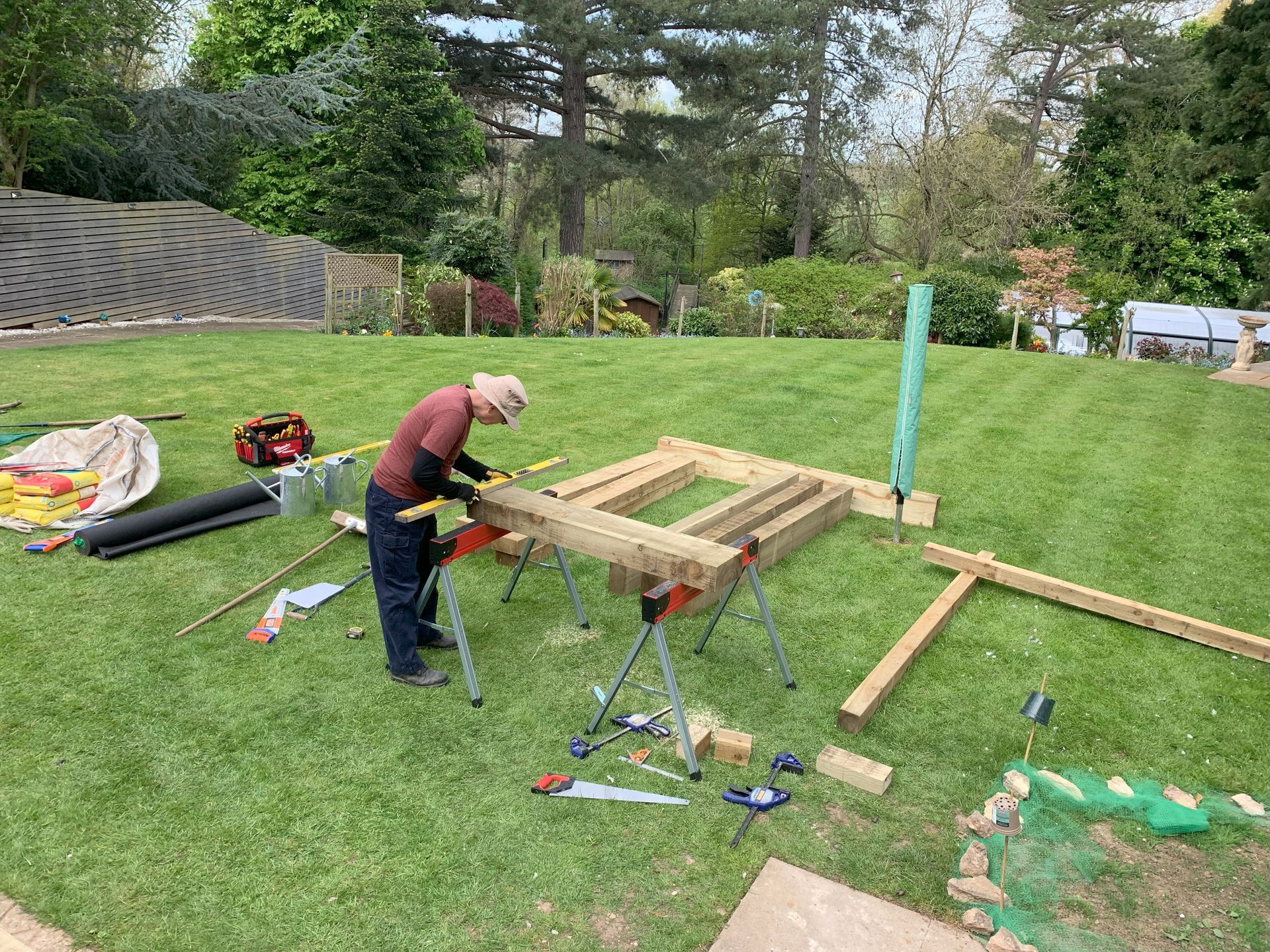 A man is working on a wooden structure in a backyard.