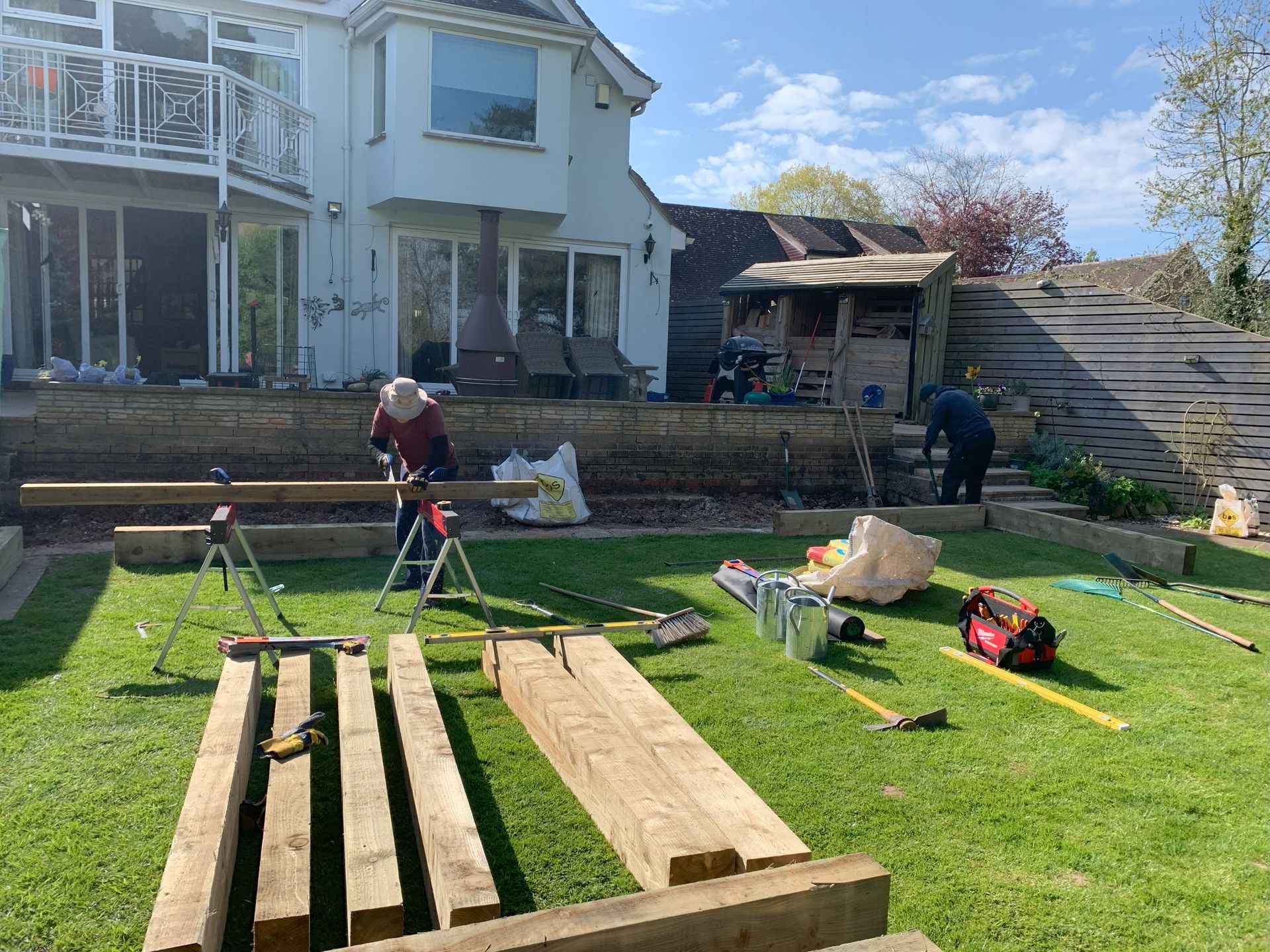 A man is working on a wooden deck in a backyard.