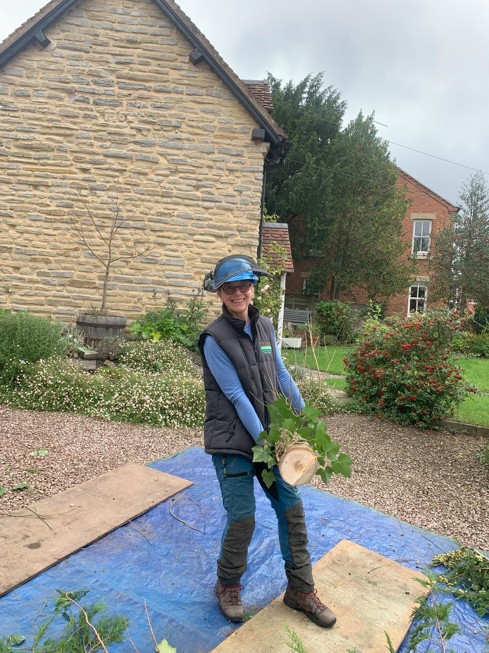 A woman is standing on a blue tarp holding a piece of wood.