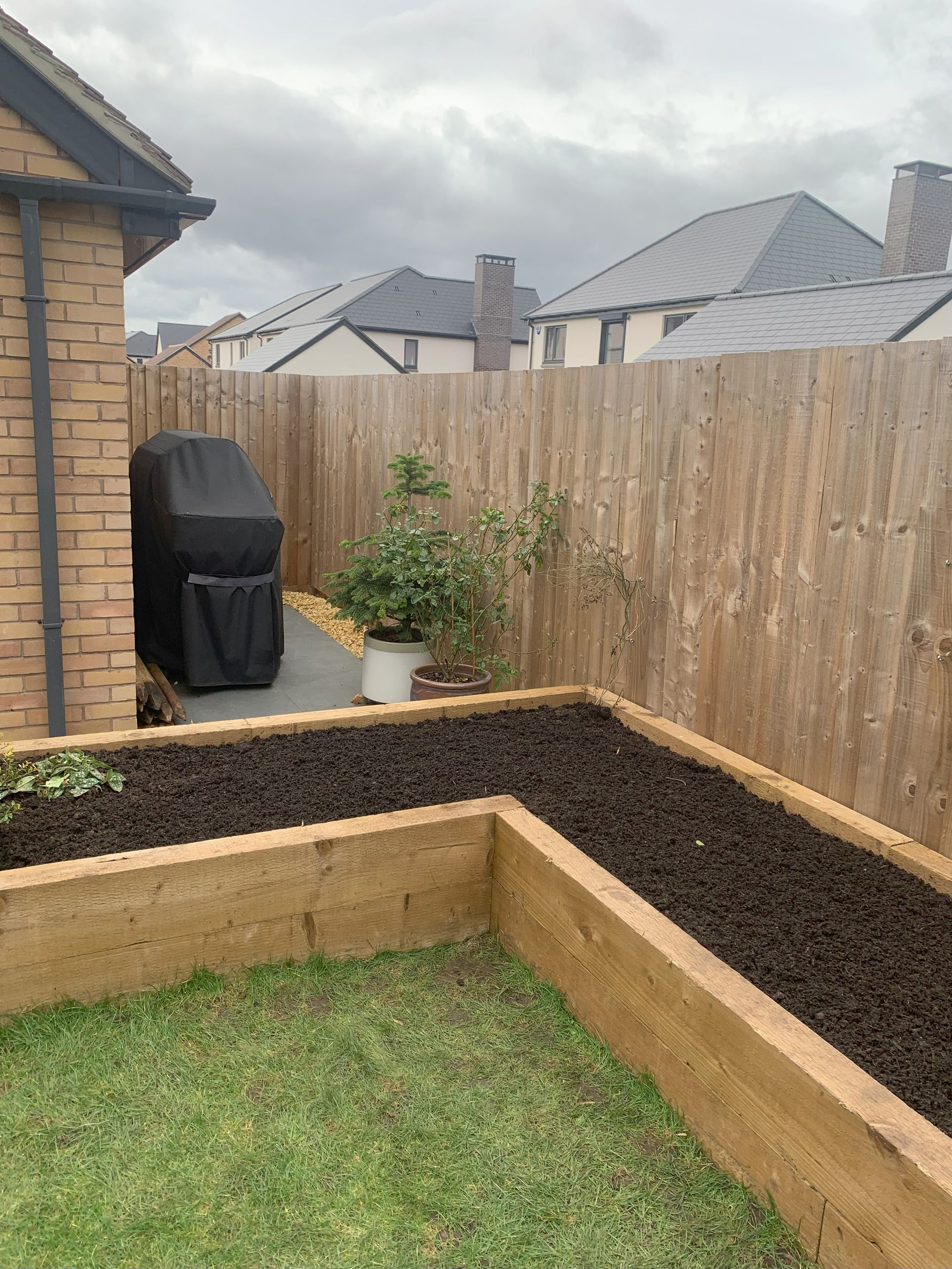 A garden with a wooden fence and a wooden planter.