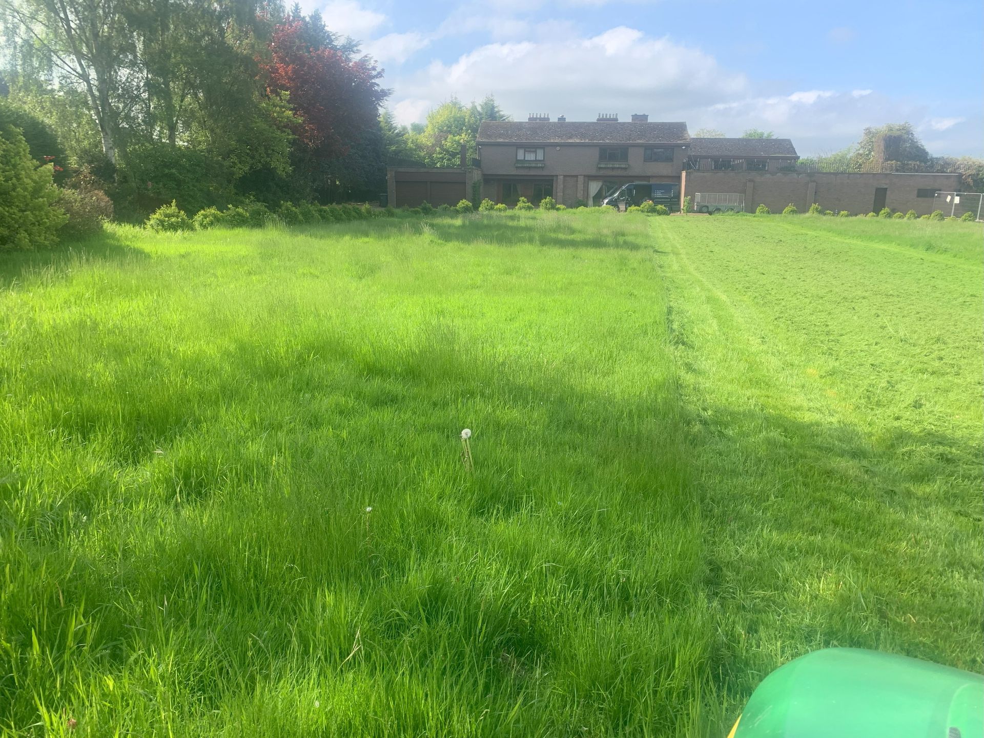 A large green field with a house in the background.
