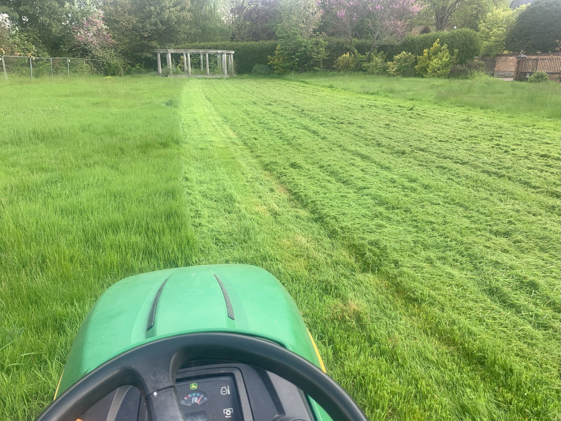 A person is riding a lawn mower through a lush green field.