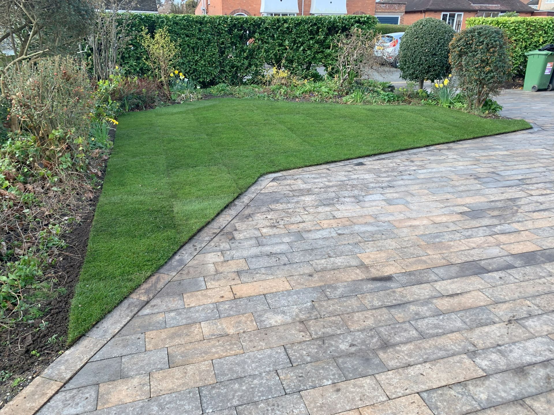 A brick driveway with a lush green lawn in the background.