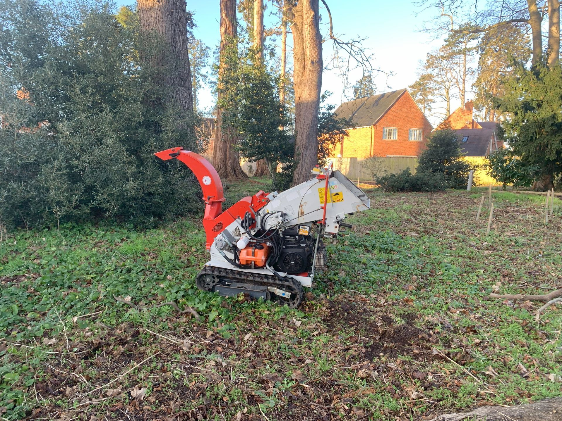 A tree chipper is sitting in the middle of a grassy field.