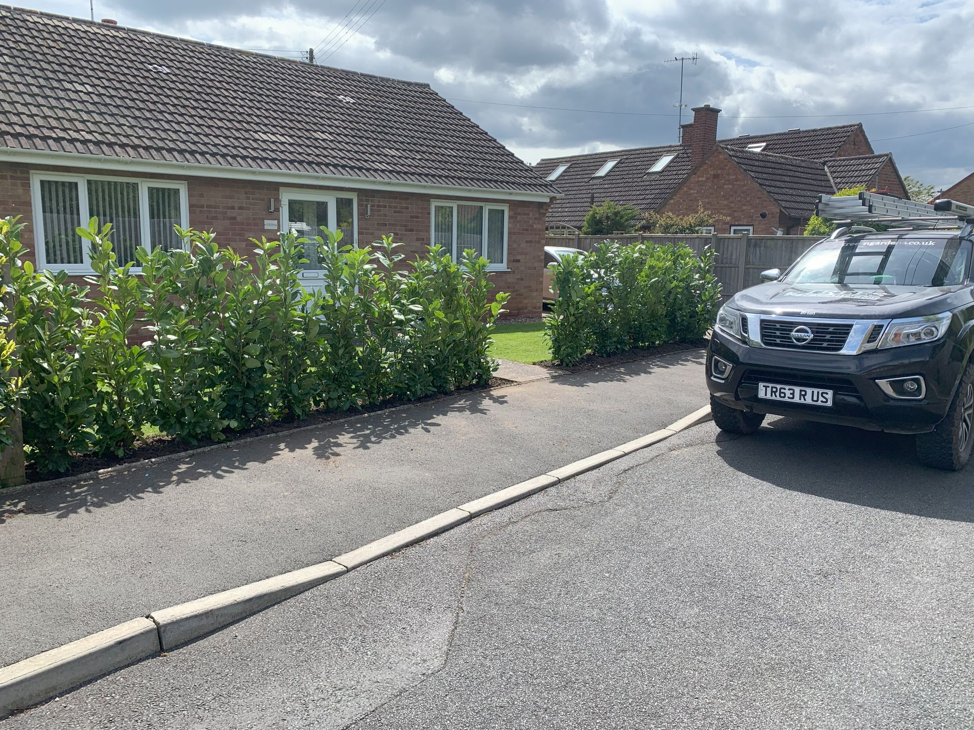 A car is parked on the side of the road in front of a house.