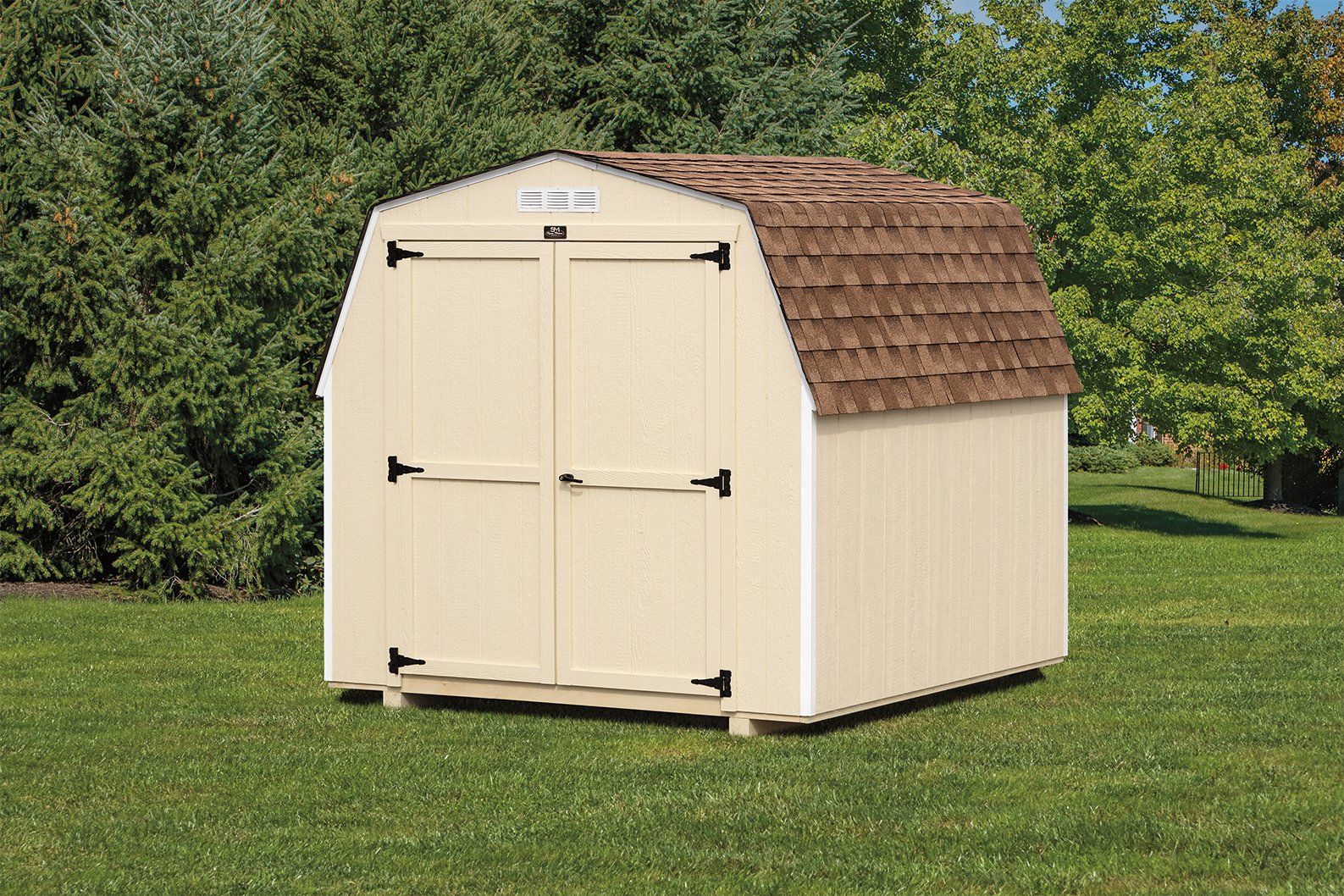 A shed with light yellow wood siding, white trim, light yellow double doors, a white gable vent, and a brown barn-style asphalt roof.