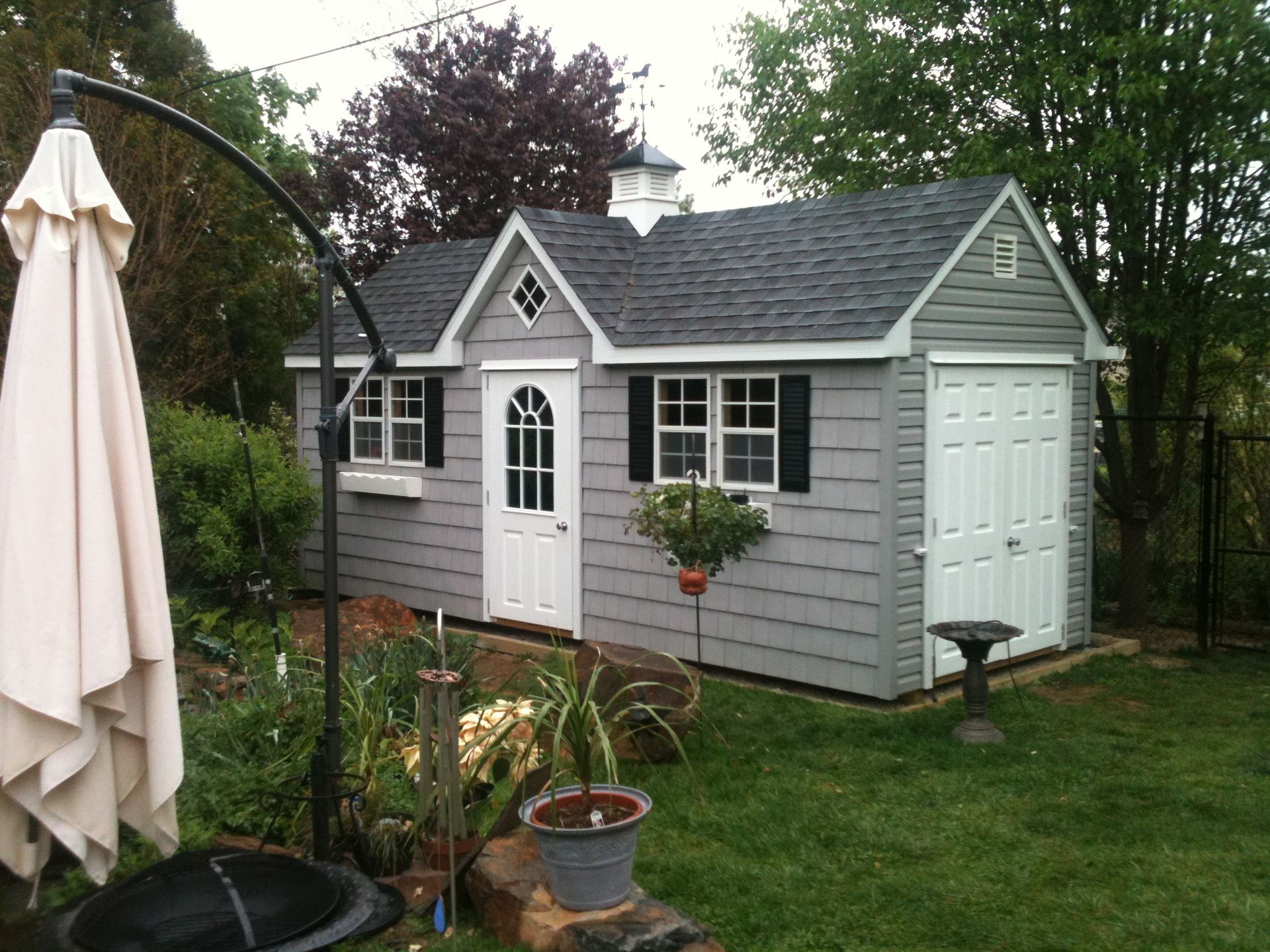 classic cottage shed with white doors and gray siding 