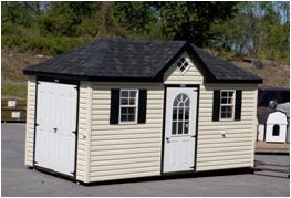 Beige vinyl siding with black trim, a set of white double doors, a white single entry side door with windows, 2 white windows with back shutters, and a black asphalt roof.