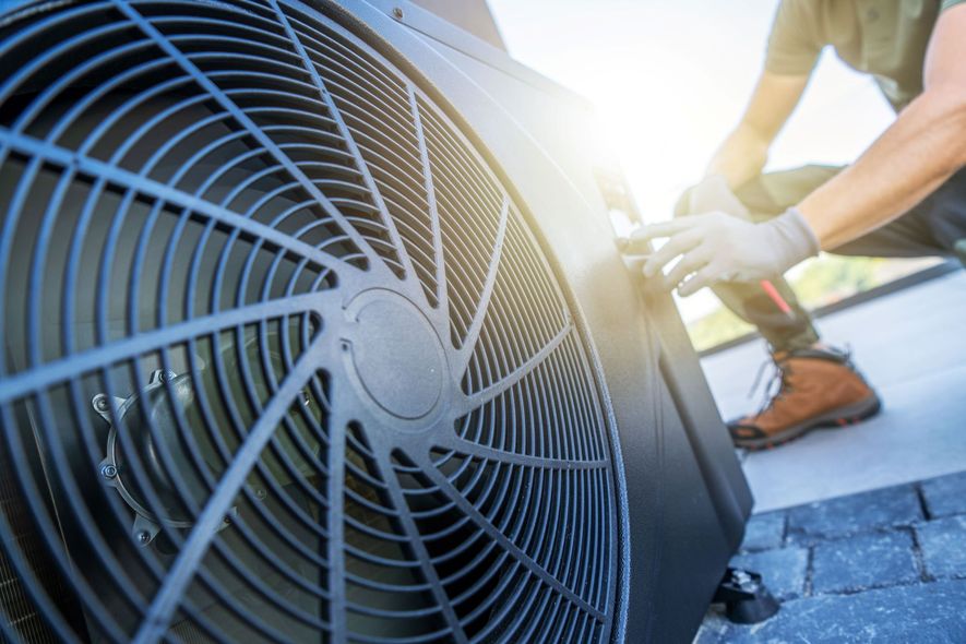 HVAC technician working on an outdoor air conditioning unit.