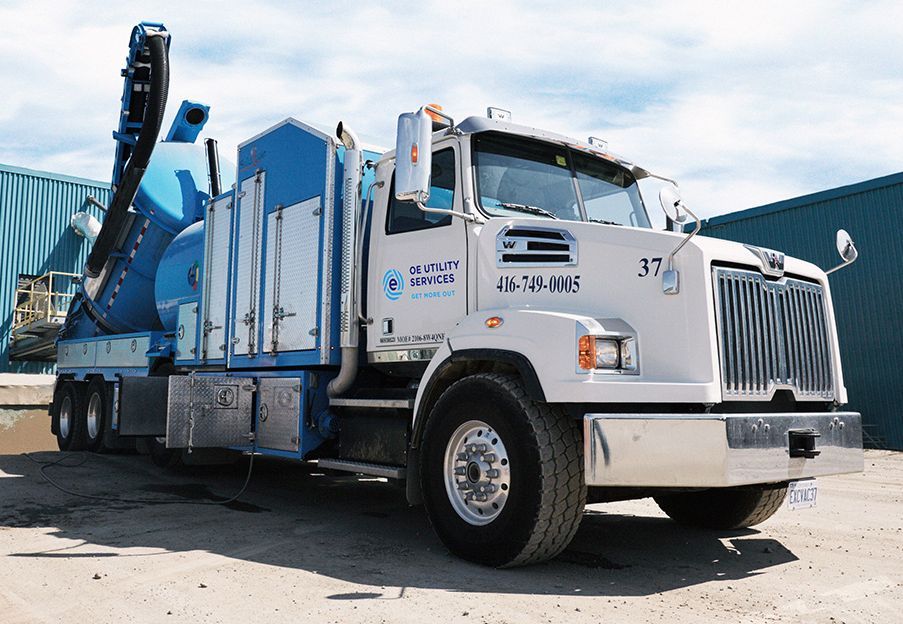 White and blue vacuum truck parked on a paved lot.