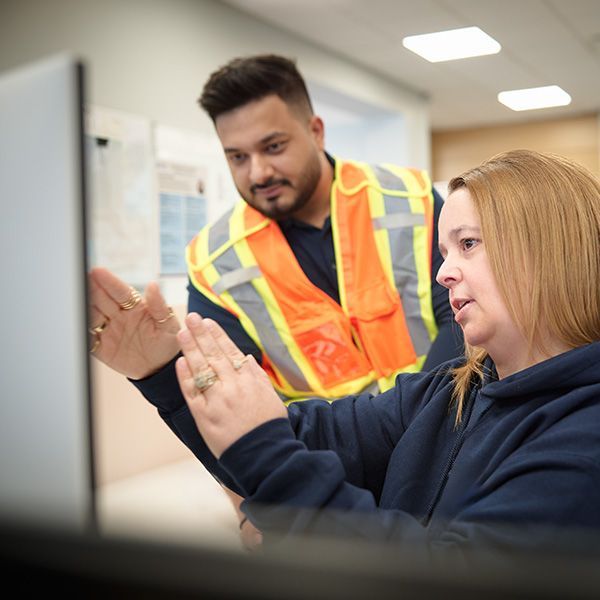 Two OE staff discussing content on a monitor
