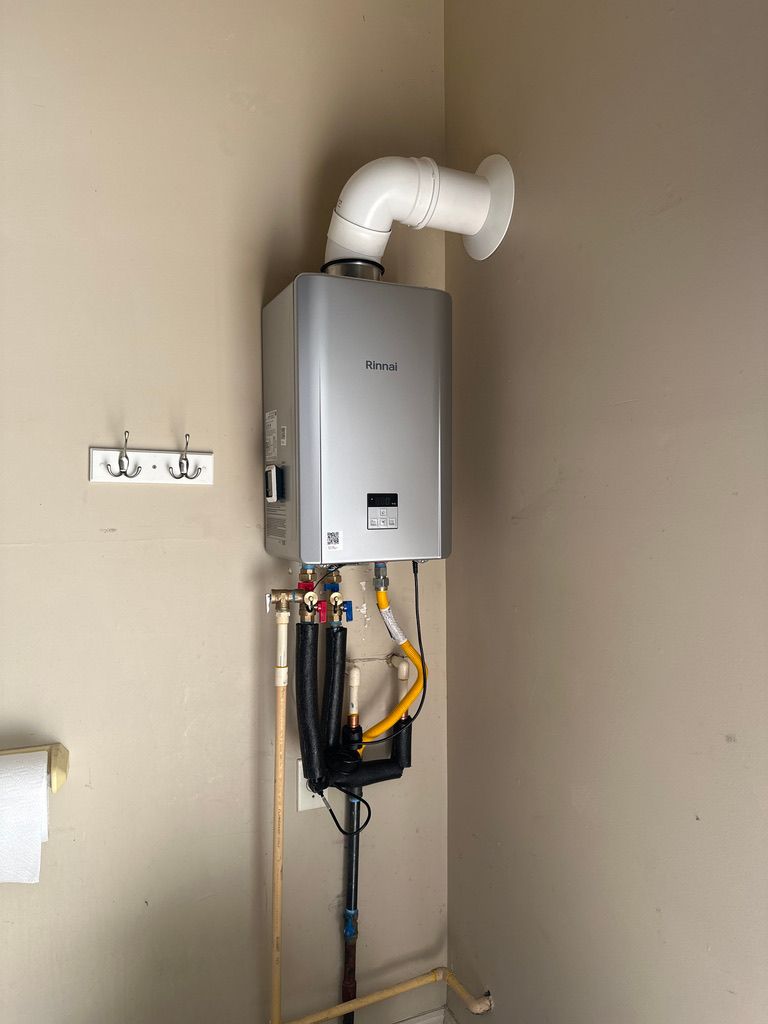 Wall-mounted water heater with white vent pipe and exposed plumbing against a beige wall.