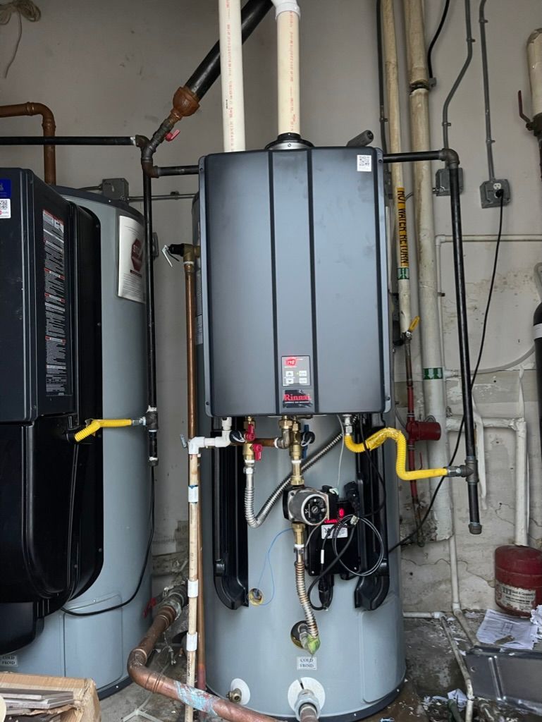 Water heater and furnace in a utility room, with pipes, vents, and yellow gas lines.