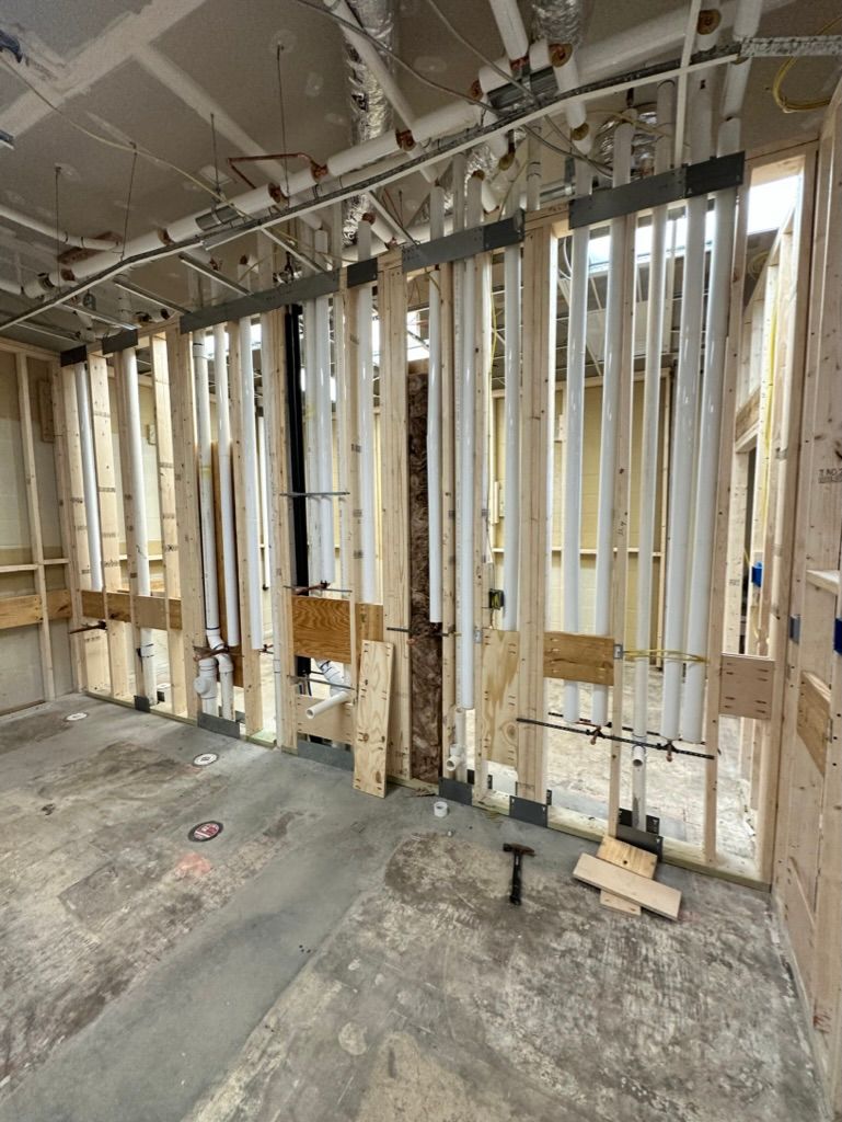 Unfinished interior wall framing with exposed studs and wiring in a construction site