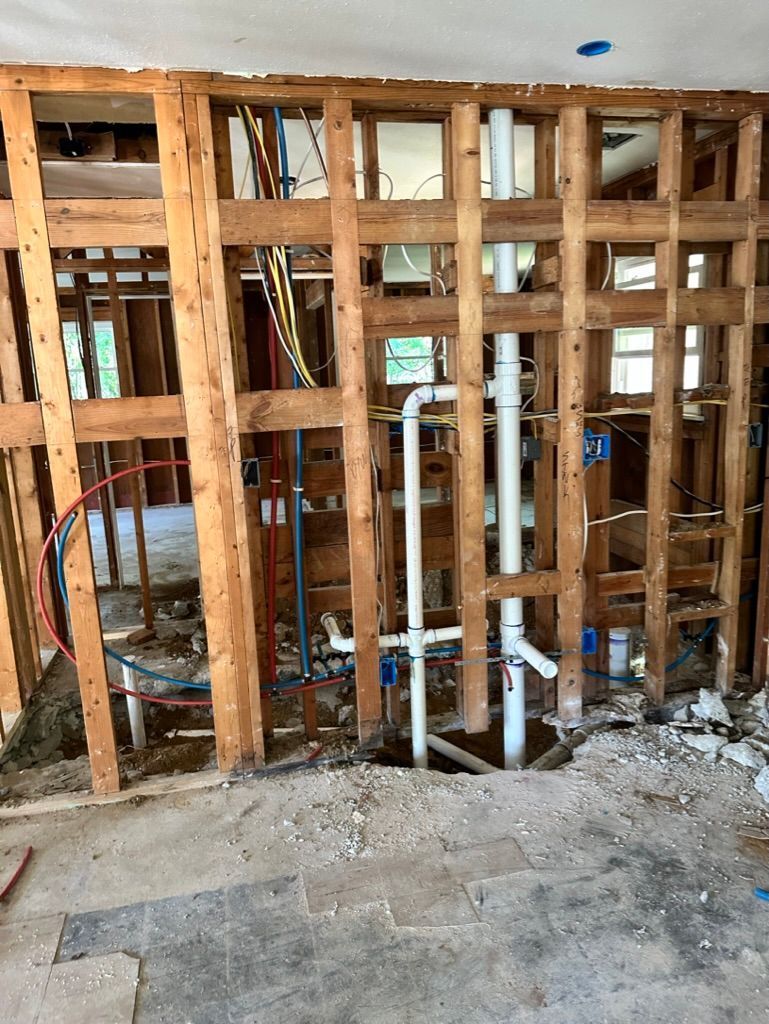 Interior wall framing under construction with exposed wooden studs and rough concrete floor.