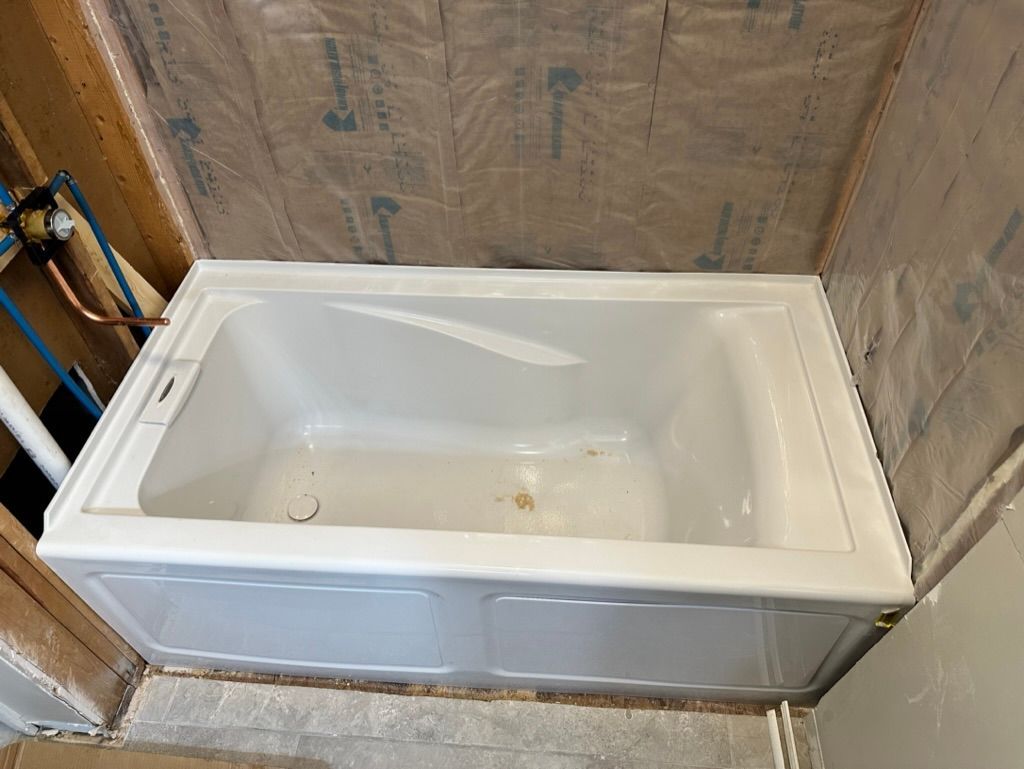 White bathtub installed in a partially finished bathroom with exposed wall framing