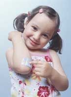 Smiling child with pigtails holding a small object against a light blue background
