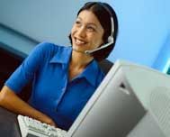 Smiling customer service agent wearing a headset at a computer