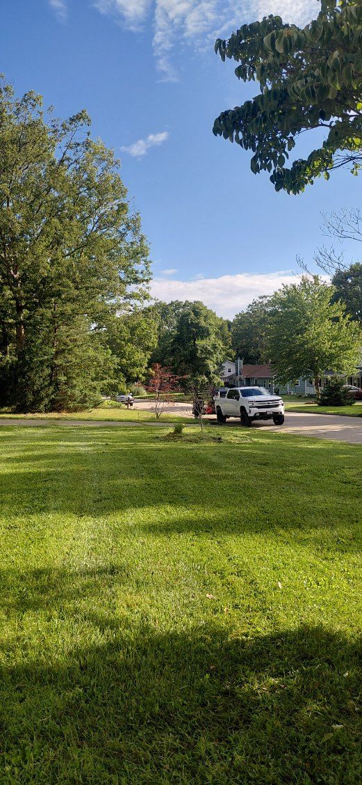 A man is raking leaves in front of a lawn mower