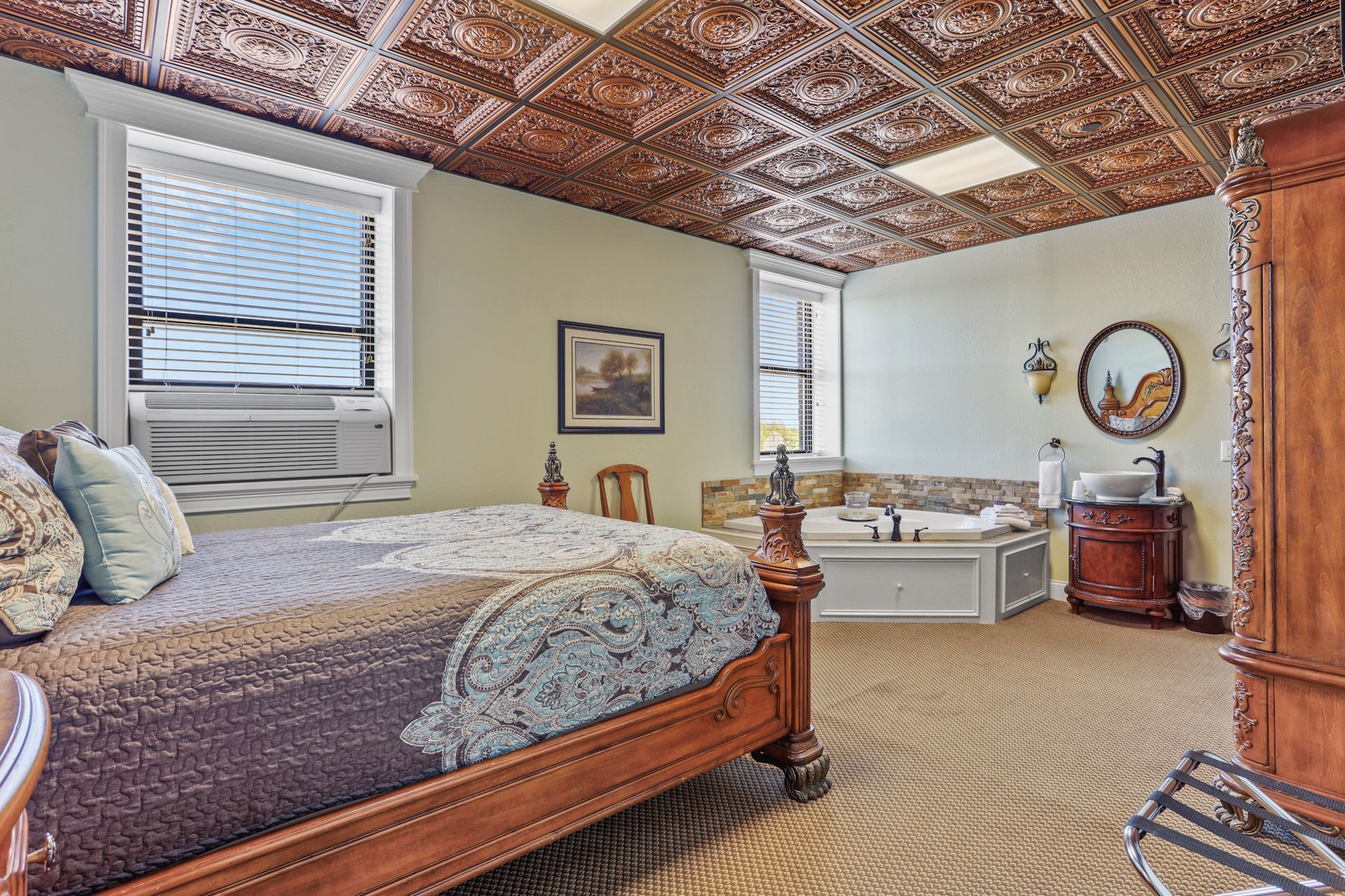 There is a large bed in the middle of the room with a copper ceiling.