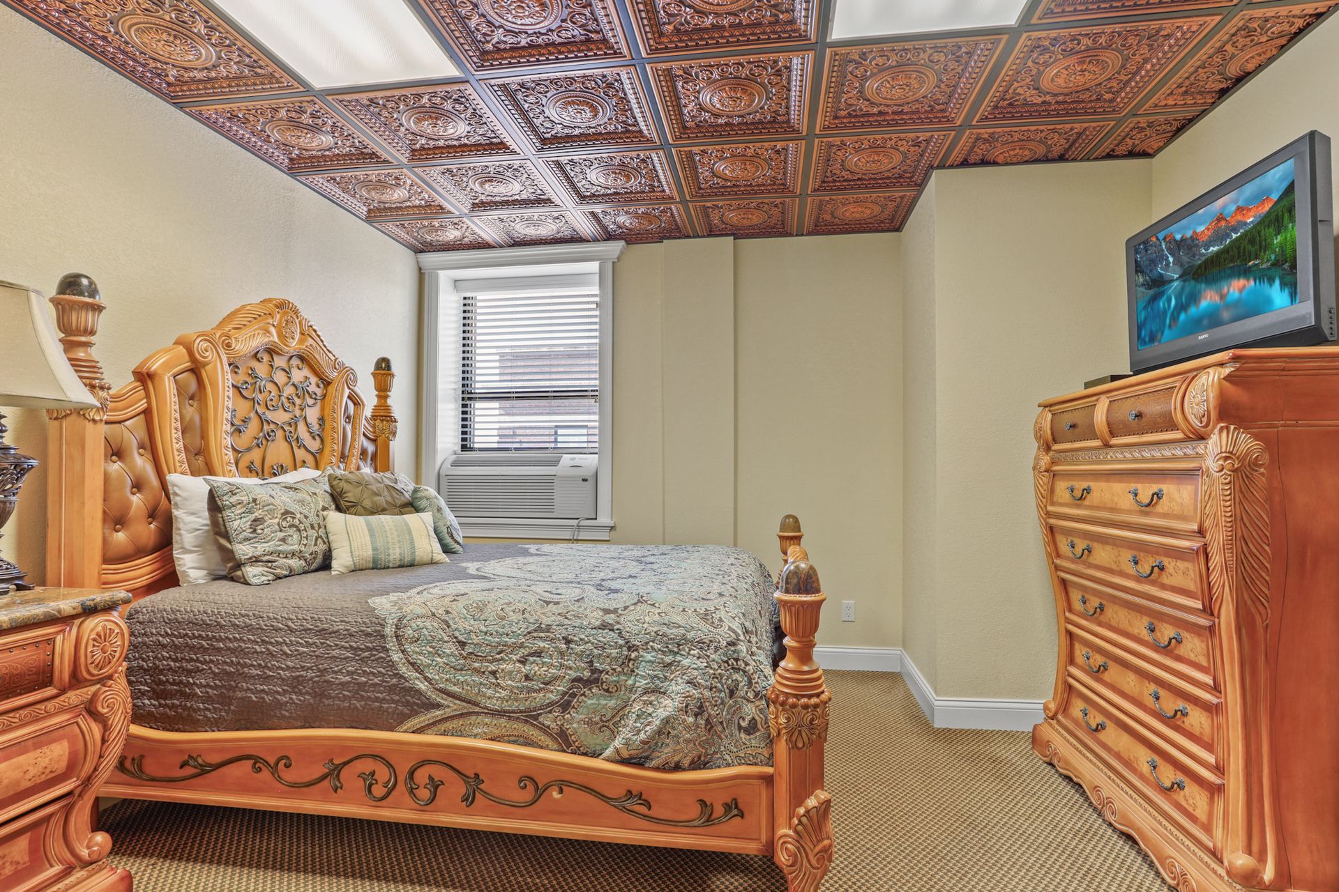 A bedroom with a bed , dresser , nightstand and television.