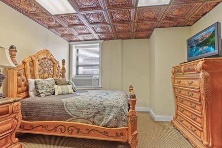 A bedroom with a bed , dresser , nightstand and television.
