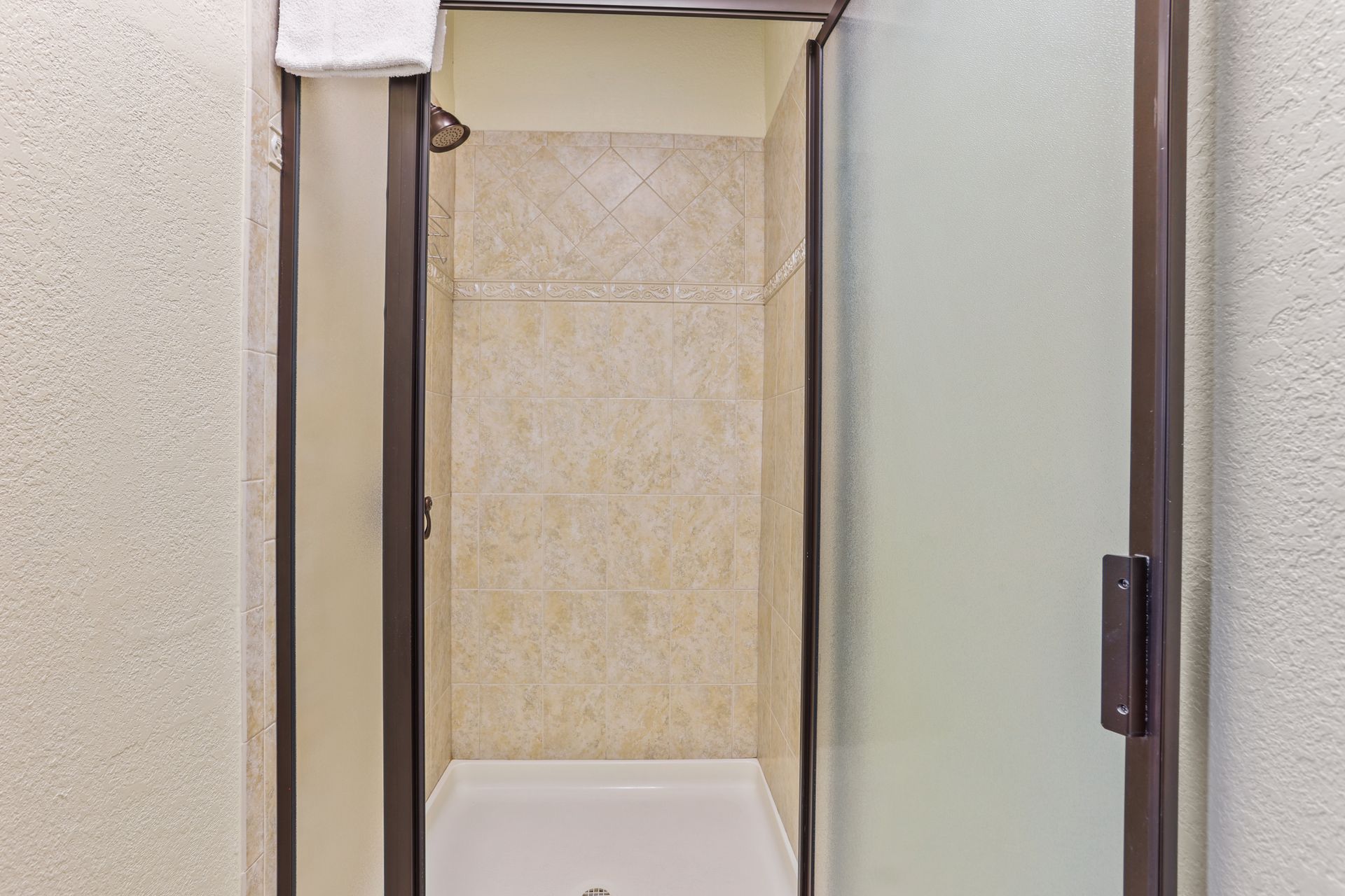 A bathroom with a walk in shower and a glass door.