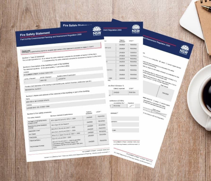 Three fire safety guidelines forms on a wooden desk with a coffee cup and notepad. — DG Electrical & Fire In Kiama, NSW