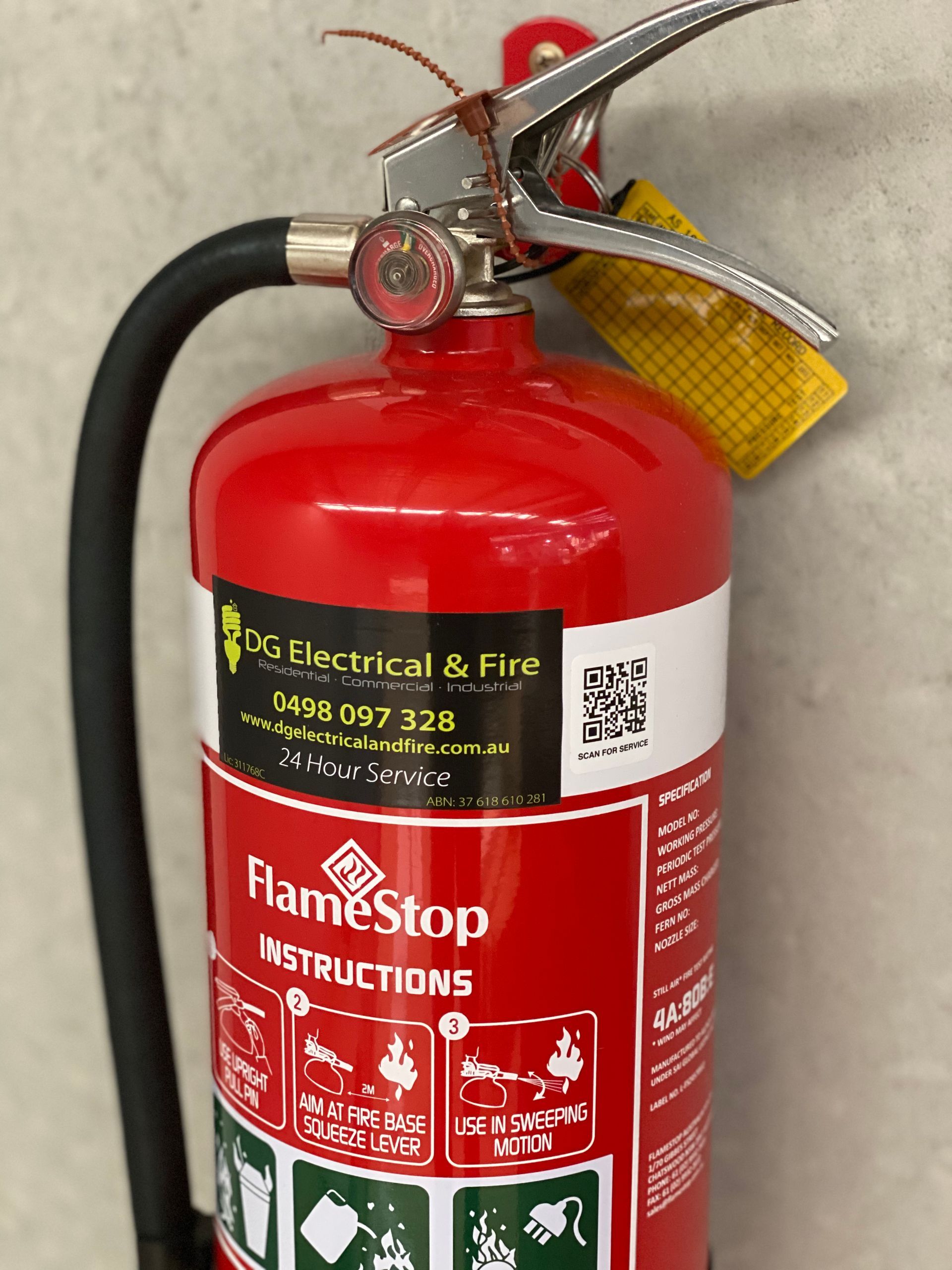Red Fire Extinguisher Mounted on a Wall With Instructions Visible — DG Electrical & Fire In Kiama, NSW