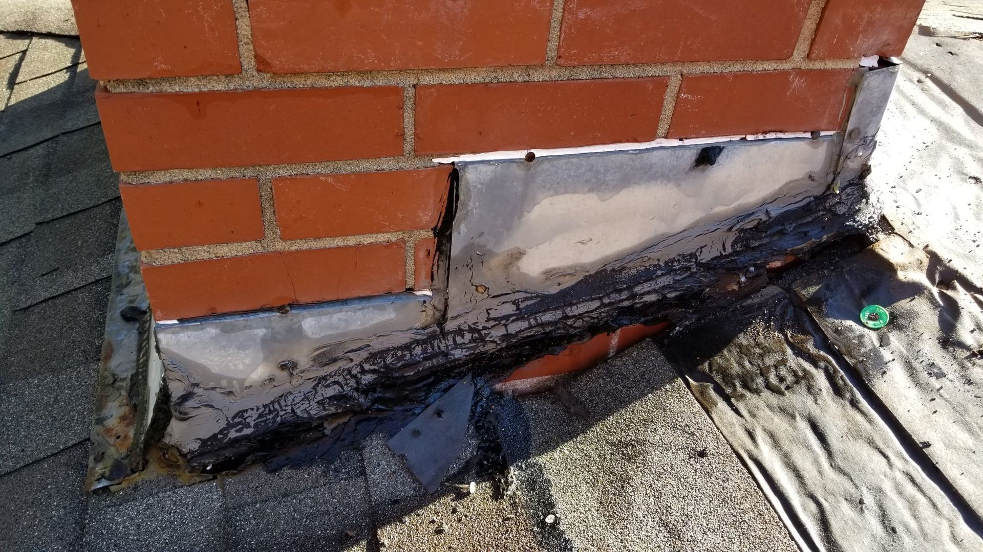A brick chimney is sitting on top of a roof.