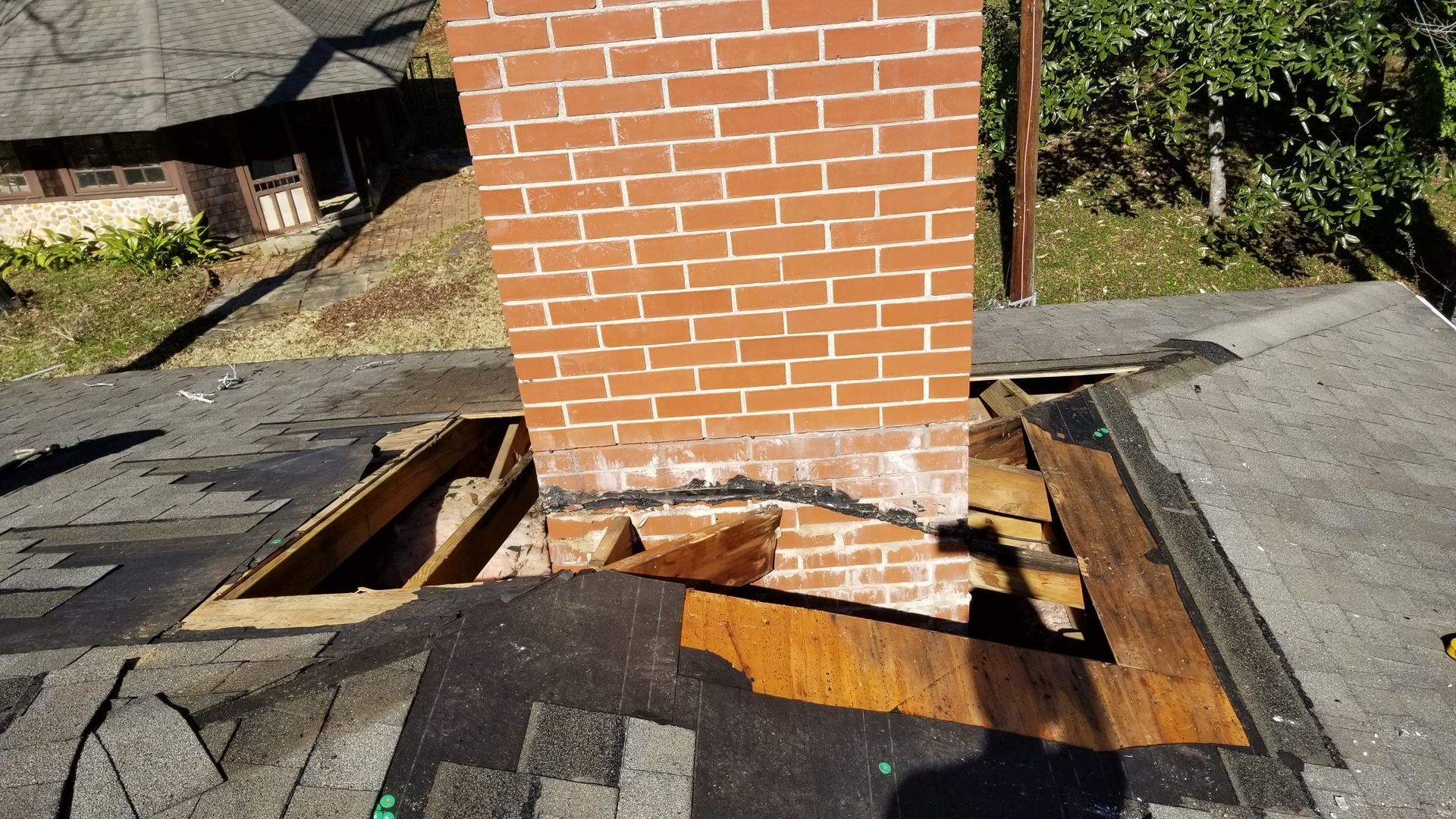 A brick chimney on top of a roof with a hole in it