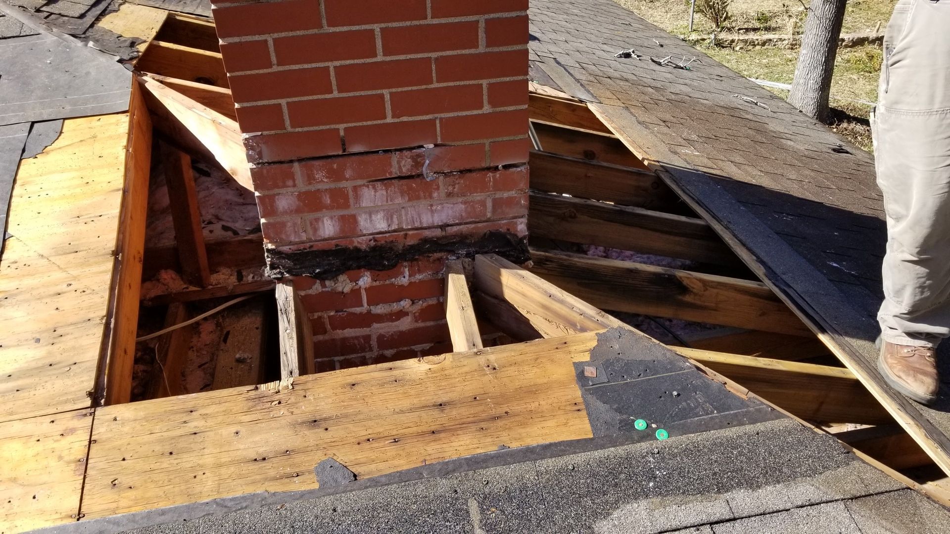 A brick chimney is being removed from a roof