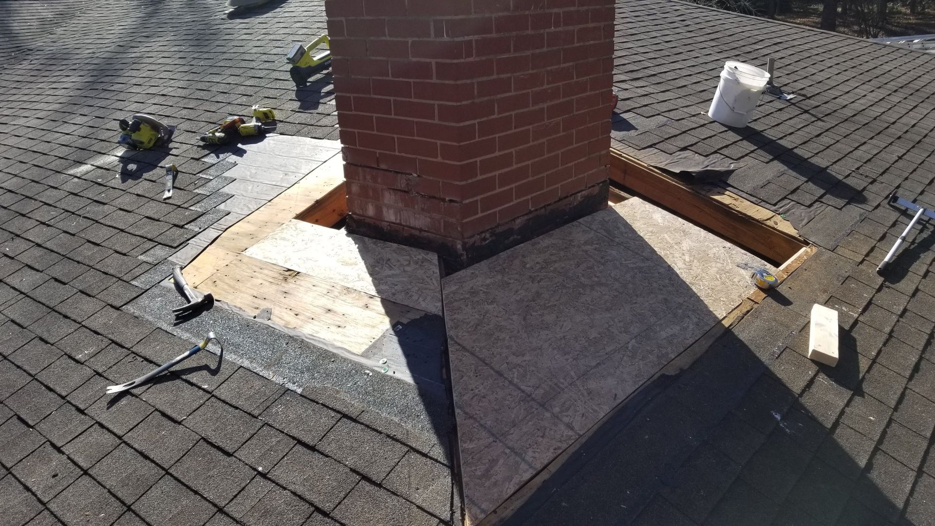 A brick chimney is being repaired on a roof