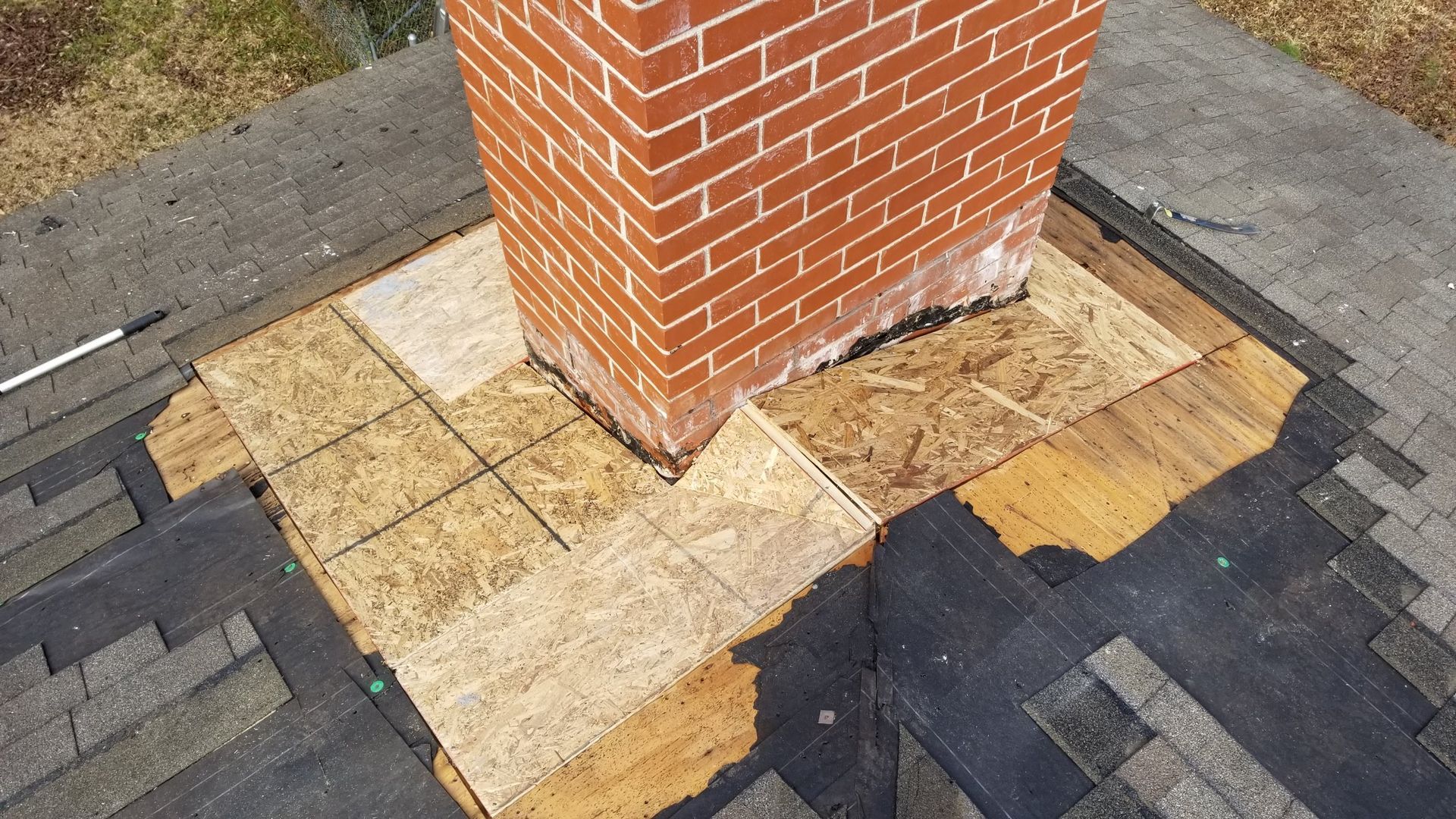 A brick chimney is sitting on top of a roof.