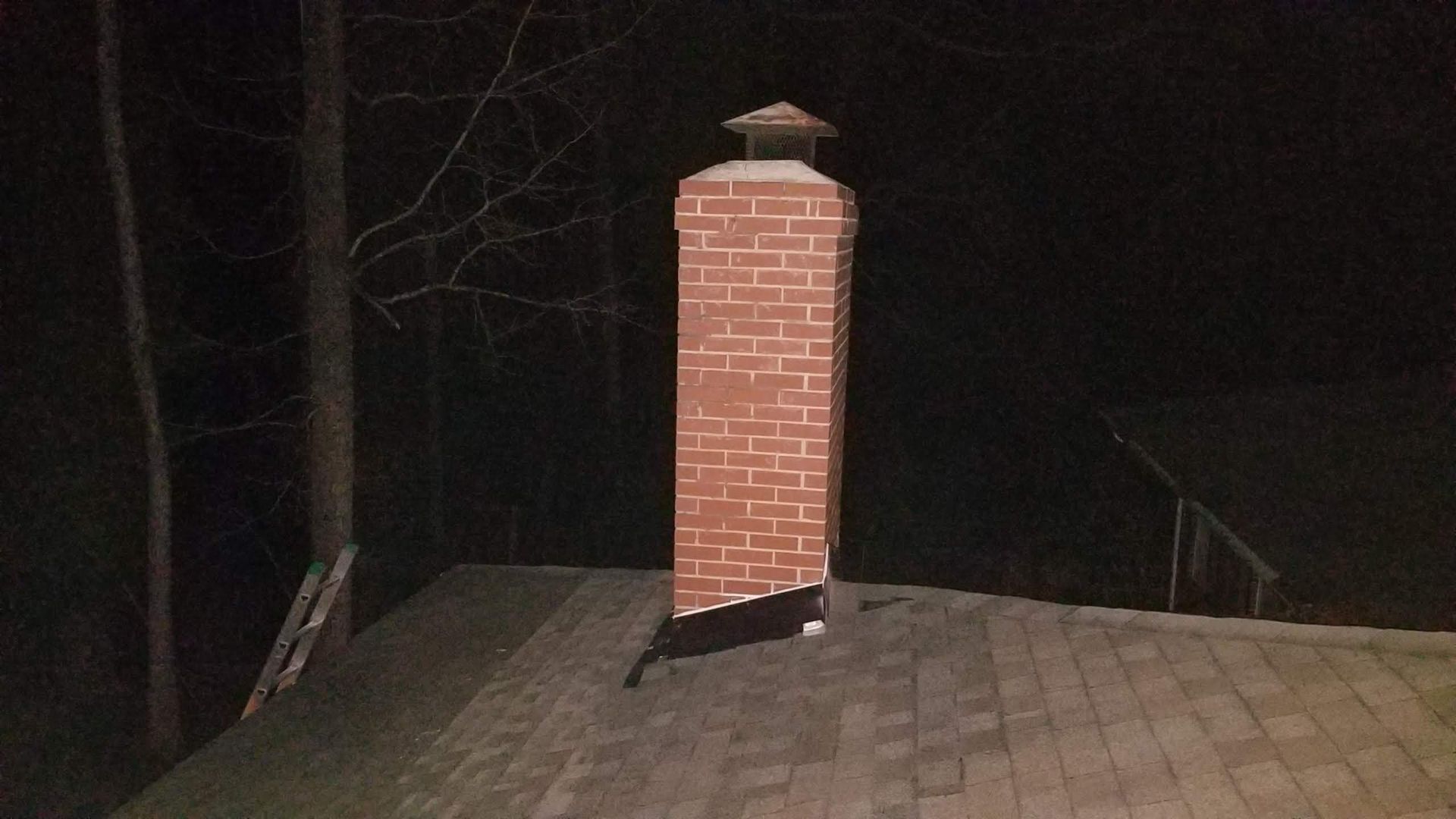 A brick chimney on top of a roof at night
