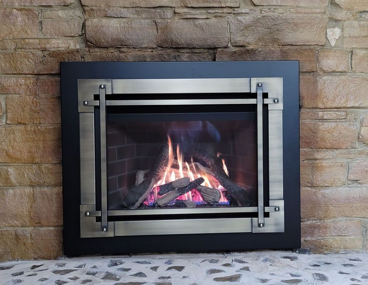 a fireplace with a black frame and a brick wall behind it
