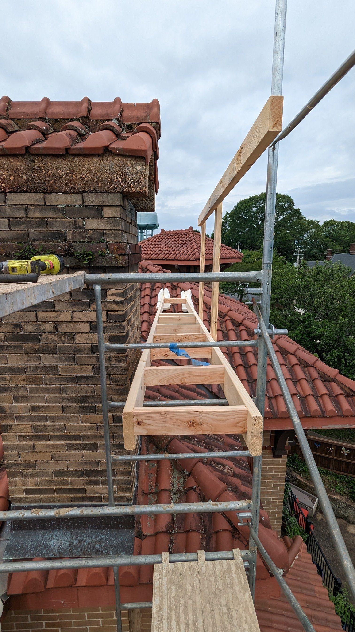 A wooden ladder is being built on top of a brick building.