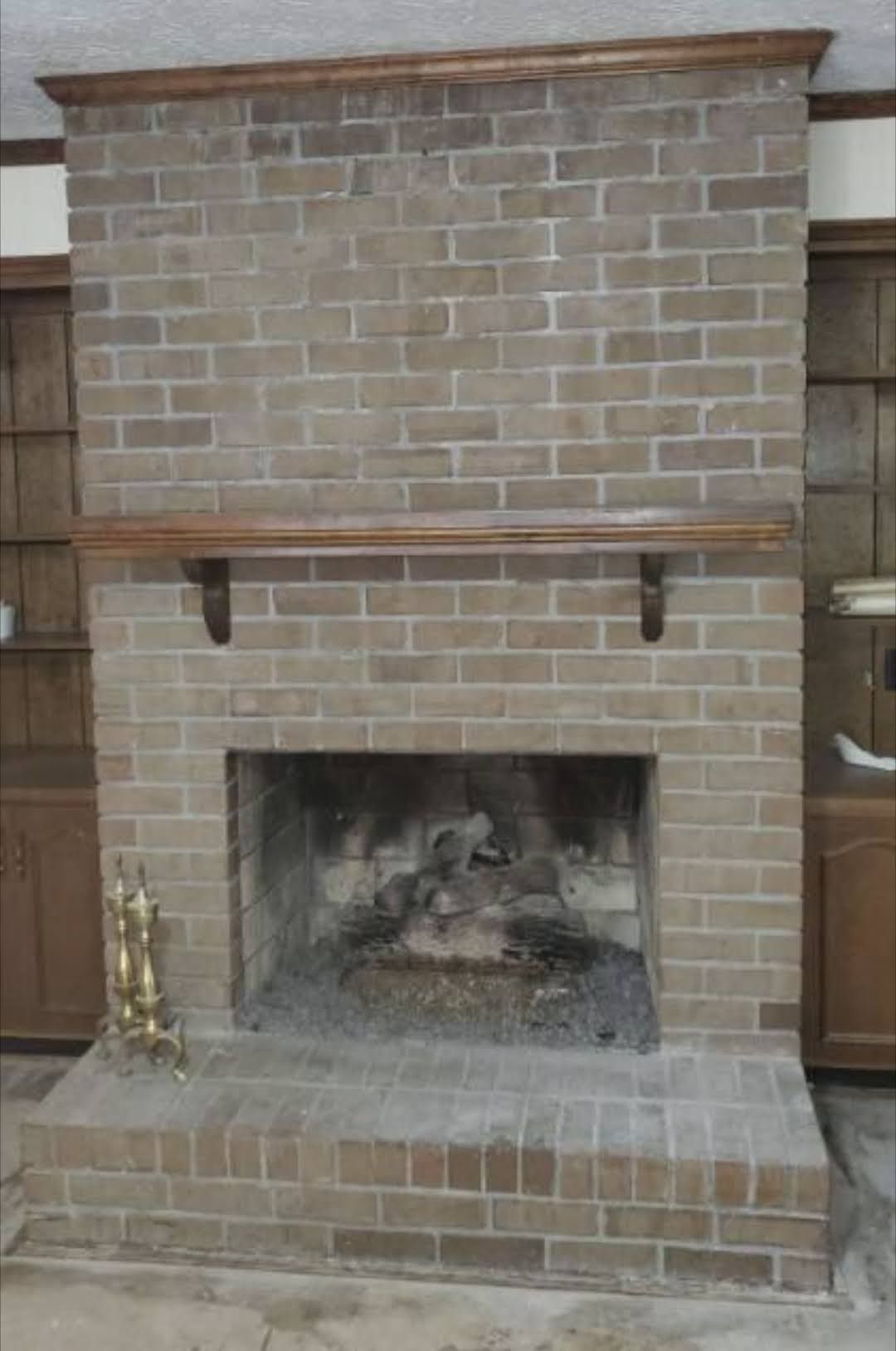 A brick fireplace with a wooden mantle in a living room.